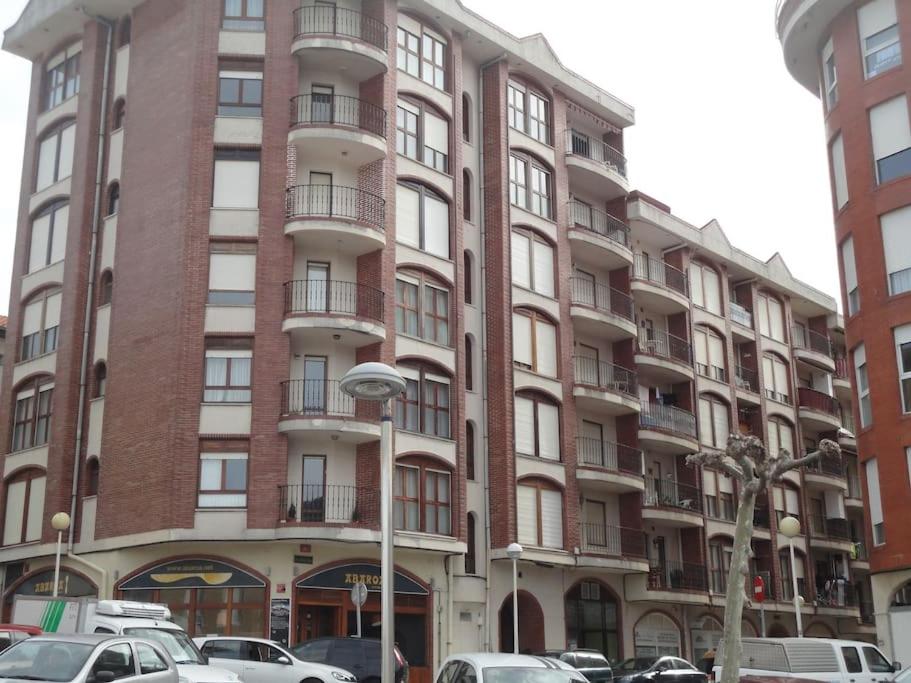 un edificio alto de ladrillo con coches estacionados frente a él en ostende, en Castro Urdiales