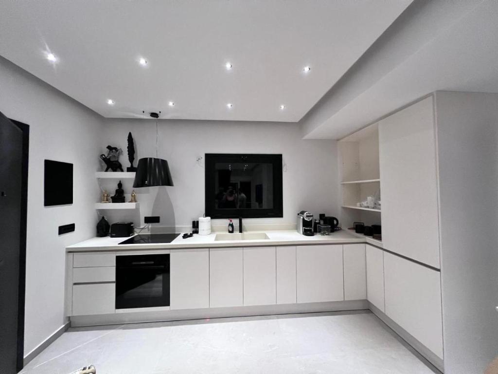拉格尼西的住宿－Lagonisi Luxury Apartment by the sea，白色的厨房设有水槽和炉灶。