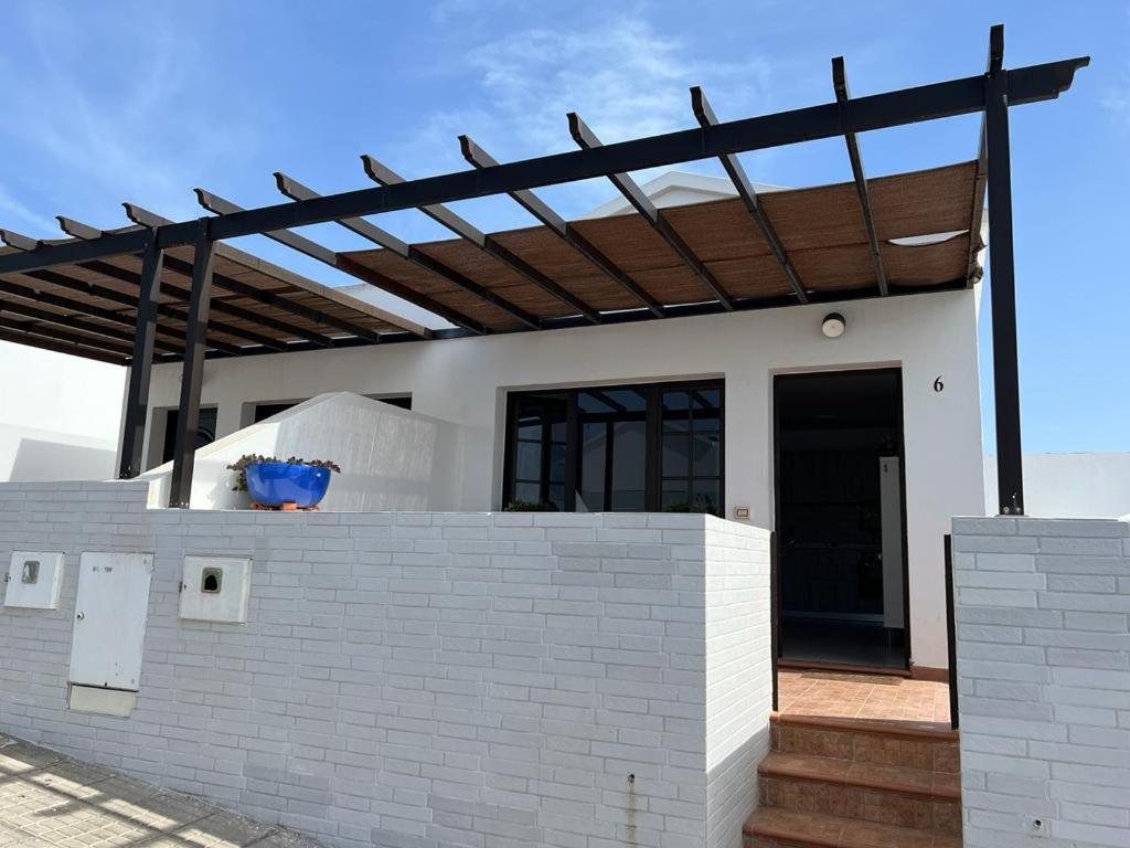 a white house with a wooden roof over a brick wall at Apartamento La Gaviota in Playa Honda