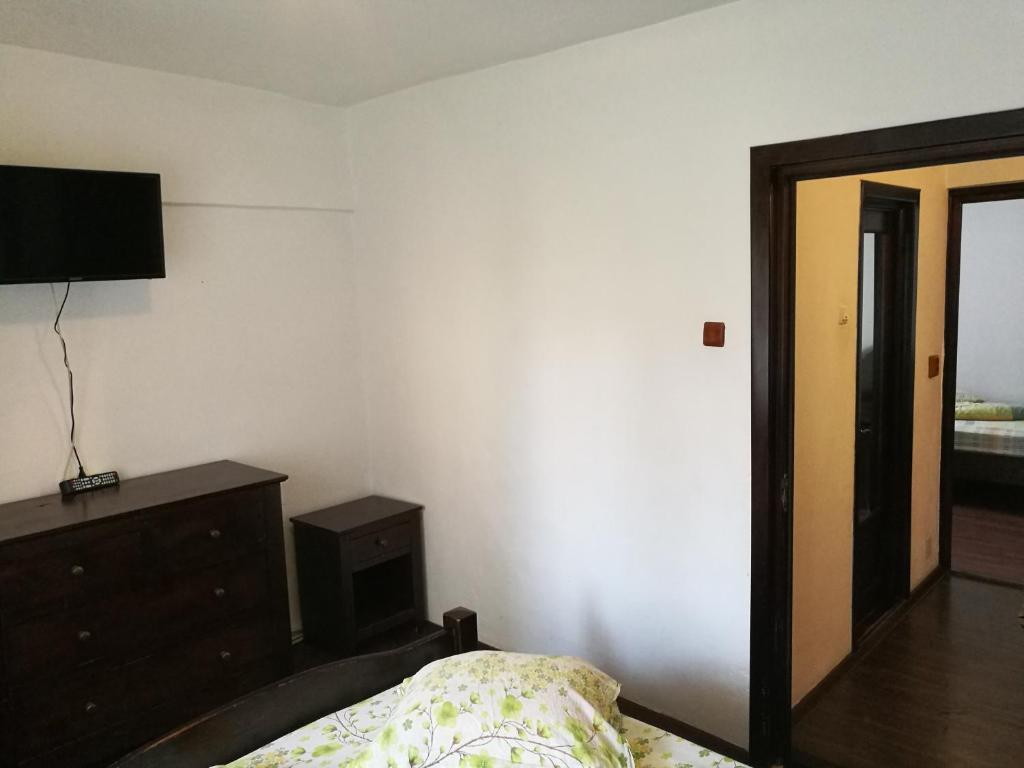 - une chambre avec un lit, une commode et une télévision dans l'établissement Apartament Slanic Moldova, à Slănic-Moldova