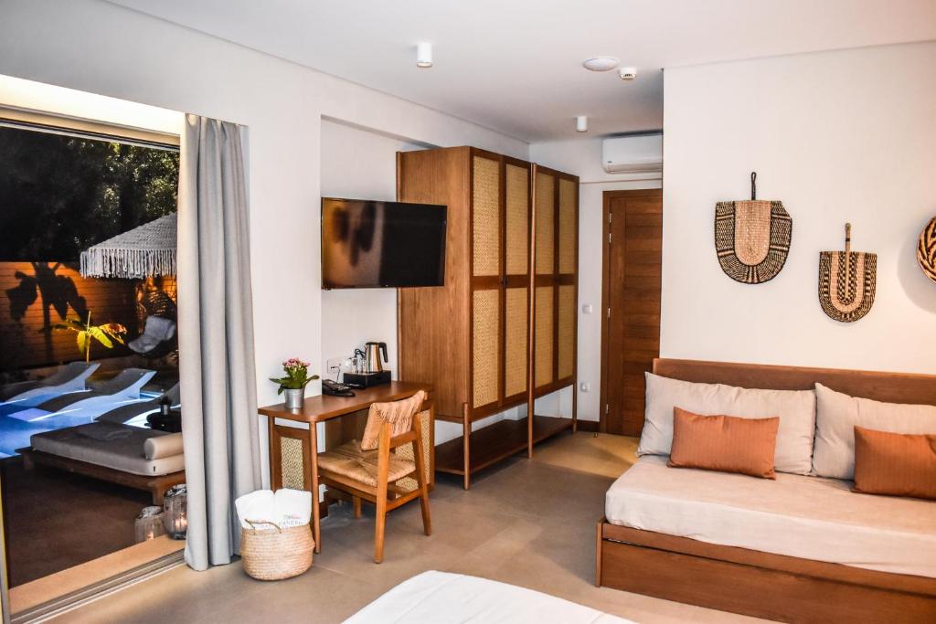 a living room with a couch and a table with a desk at Mandraki Village Boutique Hotel in Koukounaries