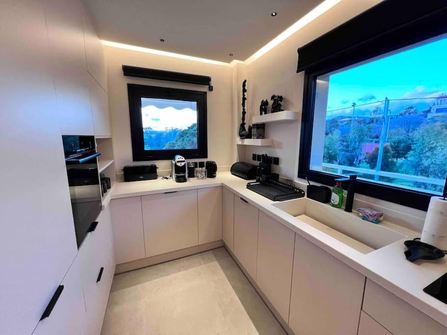 une cuisine avec des placards blancs et une grande fenêtre dans l'établissement Lagonisi 2 bedroom luxury Apartment by the sea!, à Lagonissi