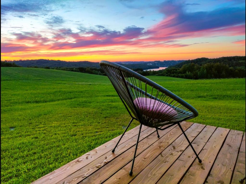 einen Stuhl auf einer Holzterrasse mit Sonnenuntergang in der Unterkunft Jaśkowe Wzgórze domki na wynajem, balia, Szymbark DOMEK NR 1 in Szymbark