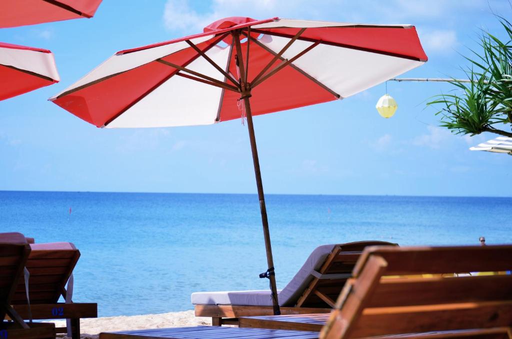 a red and white umbrella sitting on a beach at Coral Bay Resort in Phú Quốc