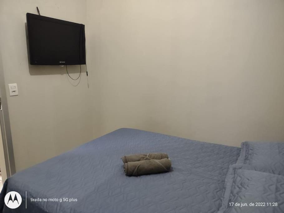 a bed with a pillow on it with a television at Studio Próximo ao centro in Palmas