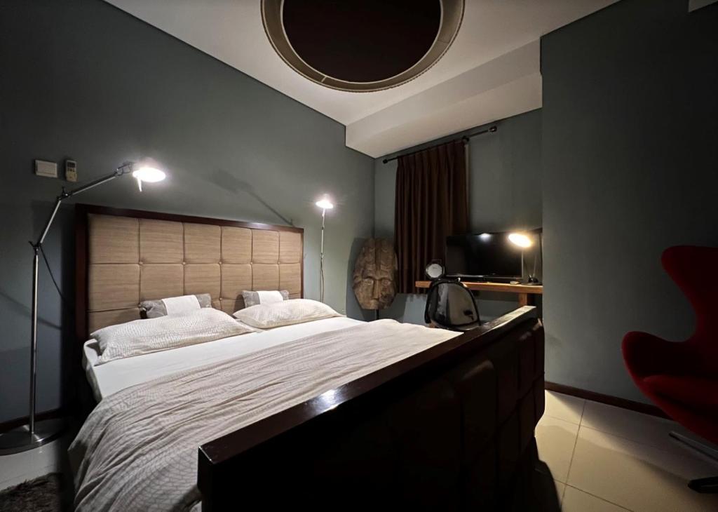 ein Schlafzimmer mit einem großen Bett mit einem großen Kopfteil in der Unterkunft 2 Bedrooms - Thamrin Executive Apartment at Jakarta Center in Jakarta