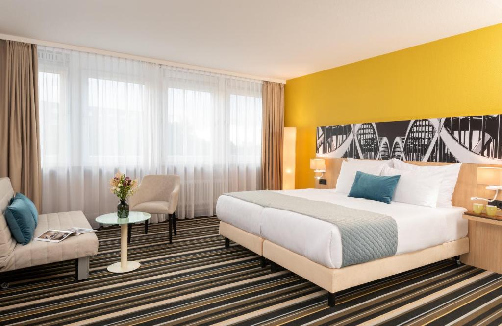 une chambre d'hôtel avec un lit et une chaise dans l'établissement Leonardo Hotel Hamburg Elbbrücken, à Hambourg