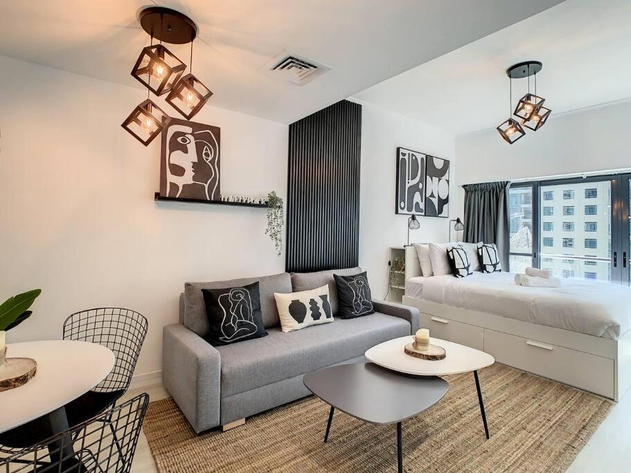 a living room with a couch and a bed and tables at Luxury Modern Studio in JLT with Amazing View & Rooftop Pool - sleeps 3 in Dubai