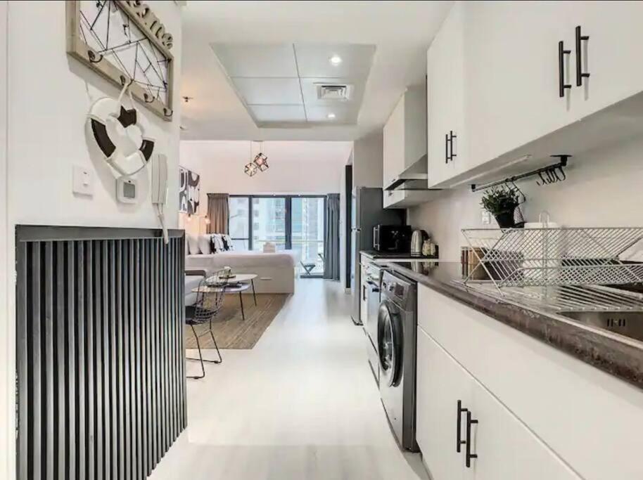 a kitchen with white cabinets and a living room at Luxury Modern Studio in JLT with Amazing View & Rooftop Pool - sleeps 3 in Dubai