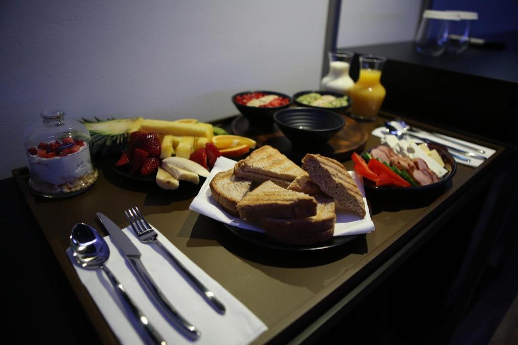 una mesa de desayuno con pan tostado y frutas y verduras en Dark Boutique Hotel, en Tirana