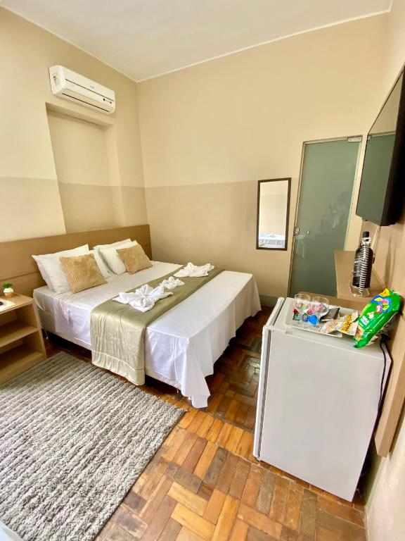 a bedroom with a white bed and a rug at Grande Hotel Minas Gerais in Siqueira Campos