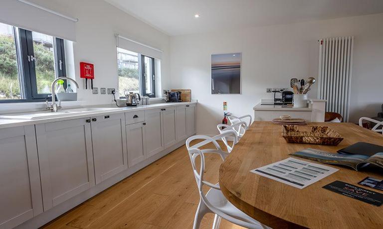 a kitchen with a wooden table and white cabinets at 15 - 3 Bedroom Cottage - LP in Nefyn