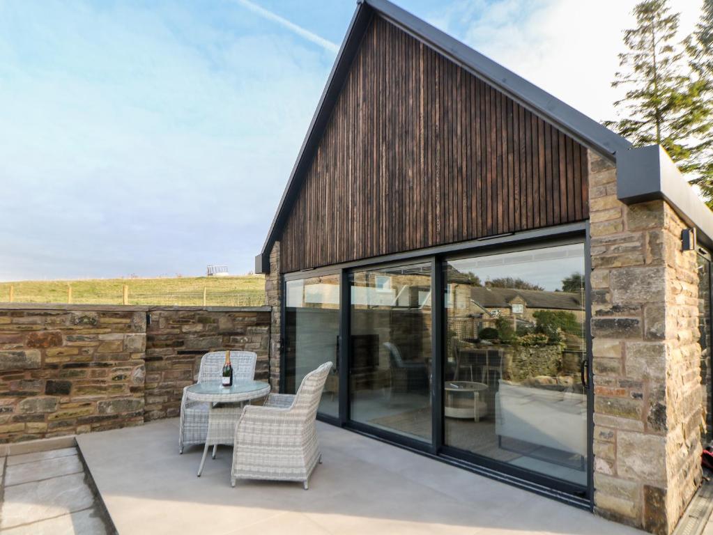 a patio with glass doors and a table and chairs at Overlea Coach House in Birch Vale