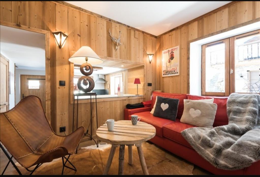 a living room with a red couch and a table at Résidence Chalet des Coeurs in Notre-Dame-de-Bellecombe