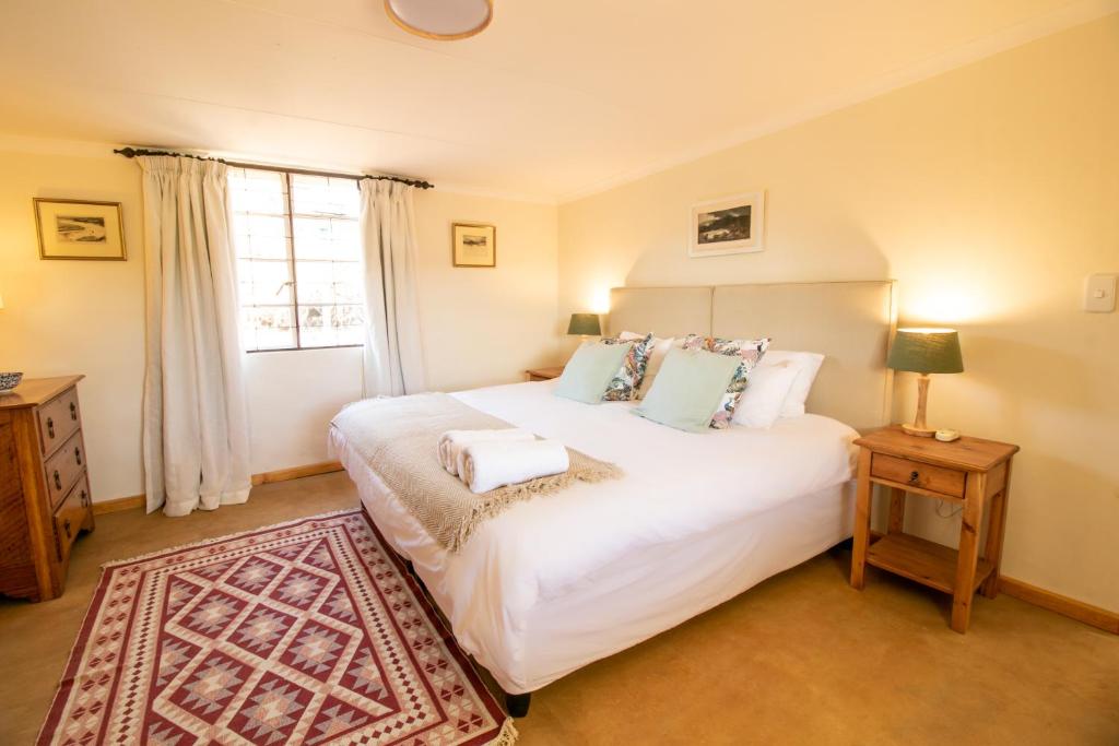 - une chambre avec un grand lit blanc et une fenêtre dans l'établissement Sunbird Cottage, à Graaff-Reinet