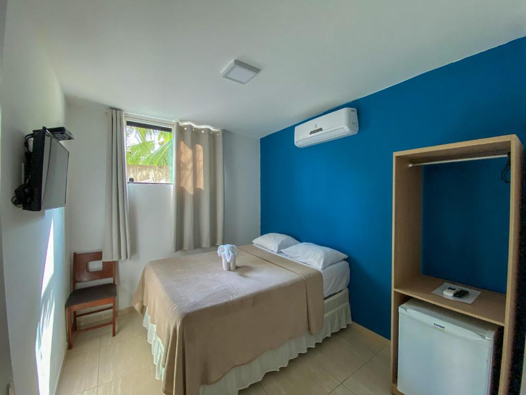 a hotel room with a bed and a blue wall at Pousada Talha - Mar in Maragogi