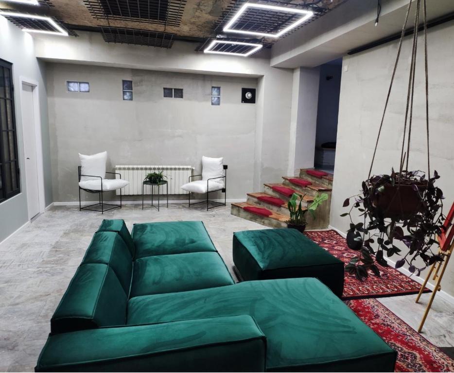 uma sala de estar com um sofá verde e cadeiras em Shared flat in an artists district Pikris Gora em Tbilisi