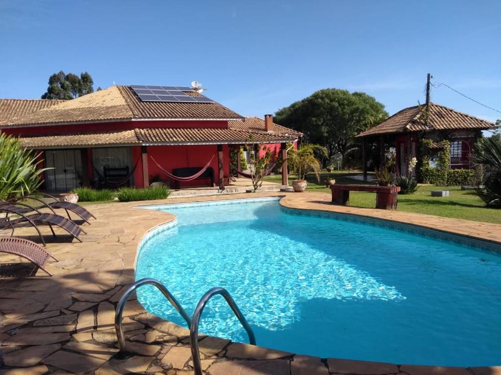 a swimming pool in front of a house at Pousada Por Do Sol chalés in Monte Verde