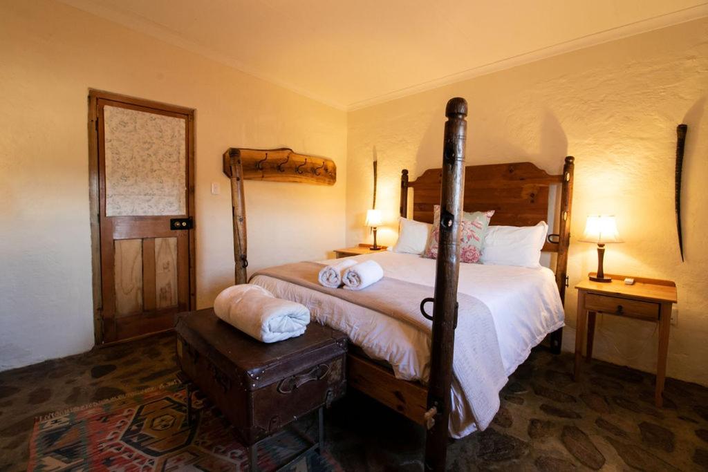 um quarto com uma cama e duas mesas de cabeceira e dois candeeiros em Wild Olive Cottage em Graaff-Reinet