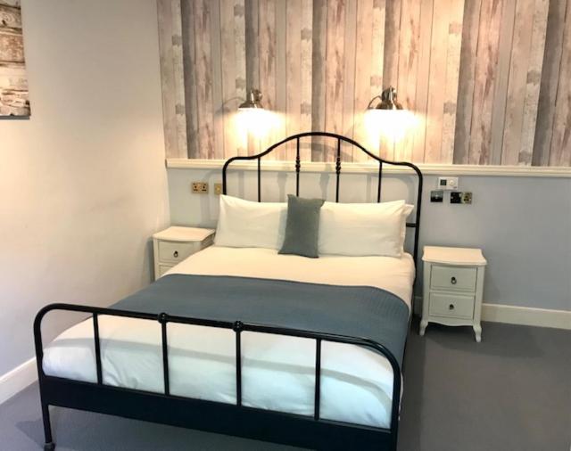 a bedroom with a bed with white pillows and two tables at Lunan House in Arbroath