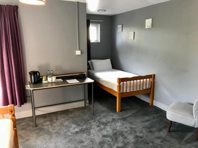 a small room with a bed and a table and a chair at Lunan House in Arbroath