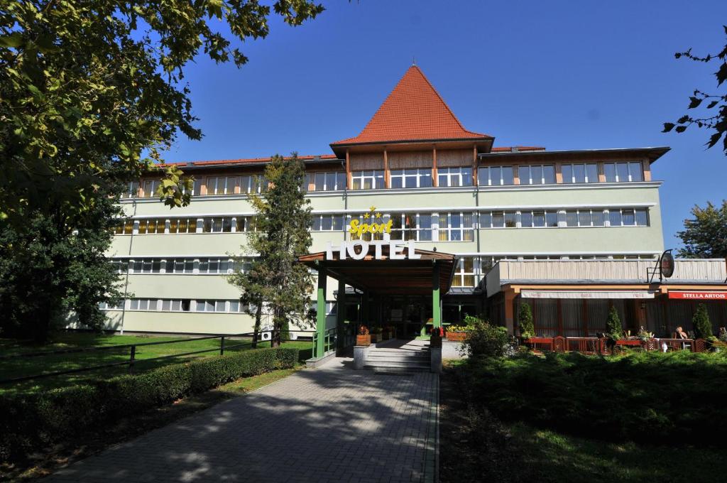 un grand bâtiment blanc avec un toit rouge dans l'établissement Sport Hotel, à Debrecen