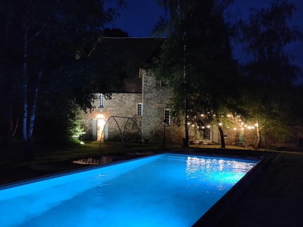 a swimming pool in front of a house at night at 17th Century Manor with Private Pool in Saint-Germain-les-Belles