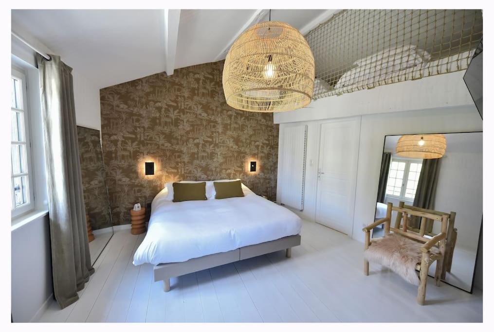 a bedroom with a large white bed and a chandelier at La Maison Rose, chaleureuse et luxueuse in Roanne