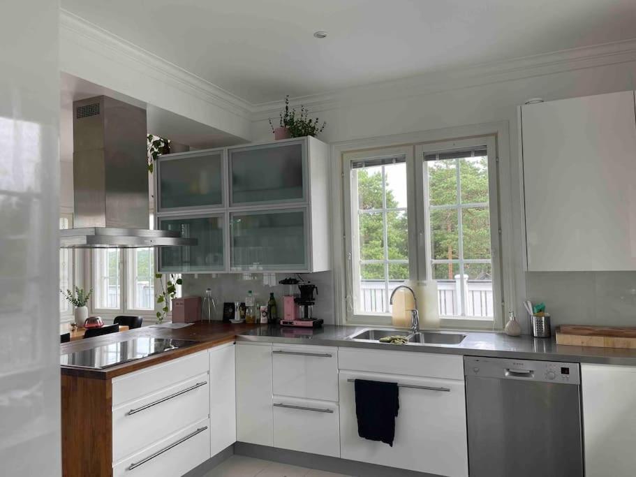 a kitchen with white cabinets and a sink and two windows at Luxury villa with stunning view in Pargas