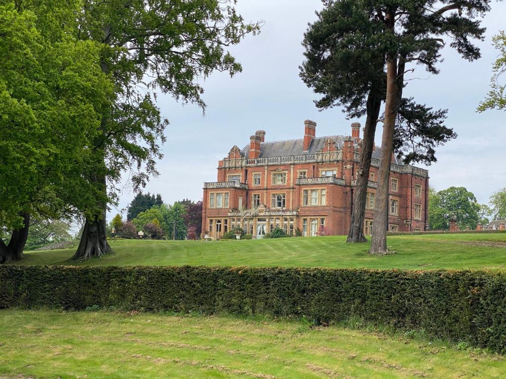 una vieja mansión con árboles delante de ella en Rossington Hall en Doncaster