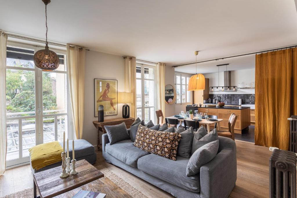 ein Wohnzimmer mit einem Sofa und einer Küche in der Unterkunft Le Monte Carlo - Appartement 3 chambres en centre ville in Rennes