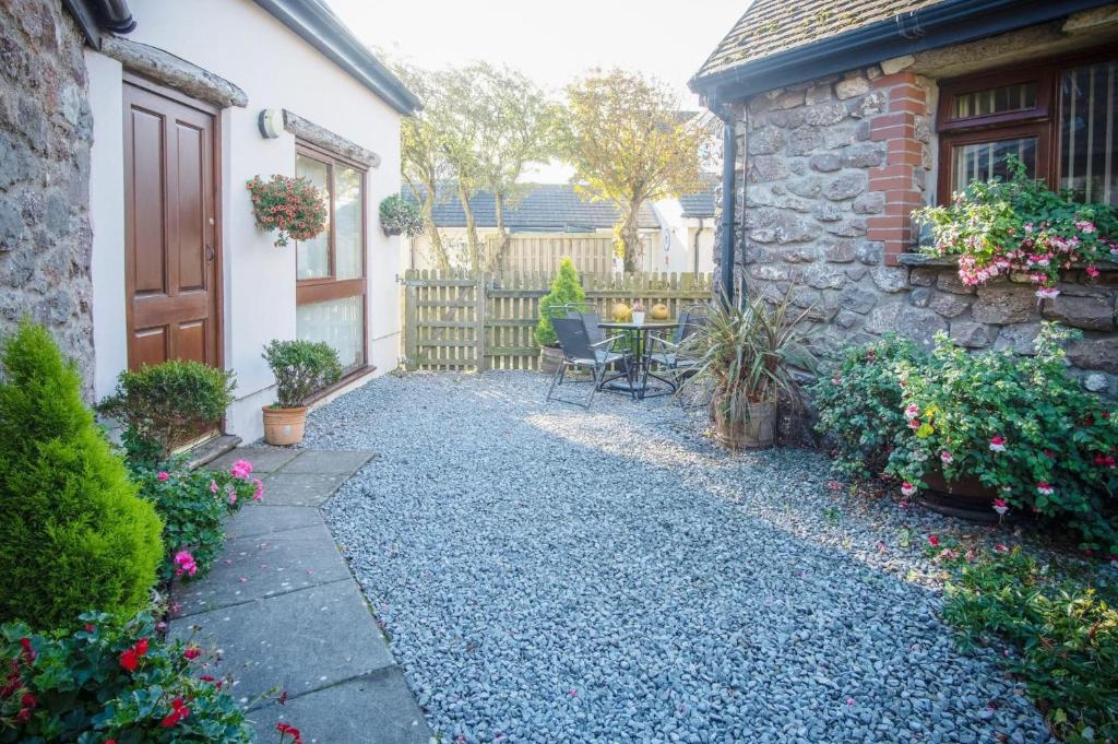 un patio con tavolo e sedie di fronte a una casa di The Old School Cottage Ship Farm - 1 Bedroom - Rhossili a Rhossili