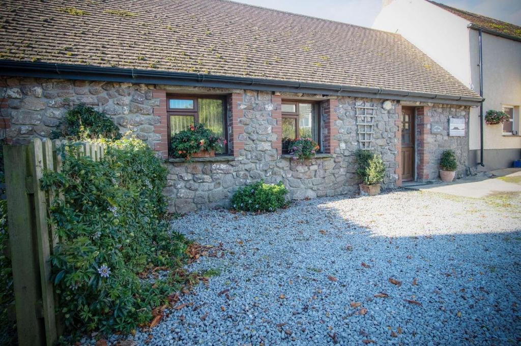 una casa de piedra con una valla delante de ella en Fferm-Llong Cottage Ship Farm - 2 Bedroom -Rhossili, en Rhossili