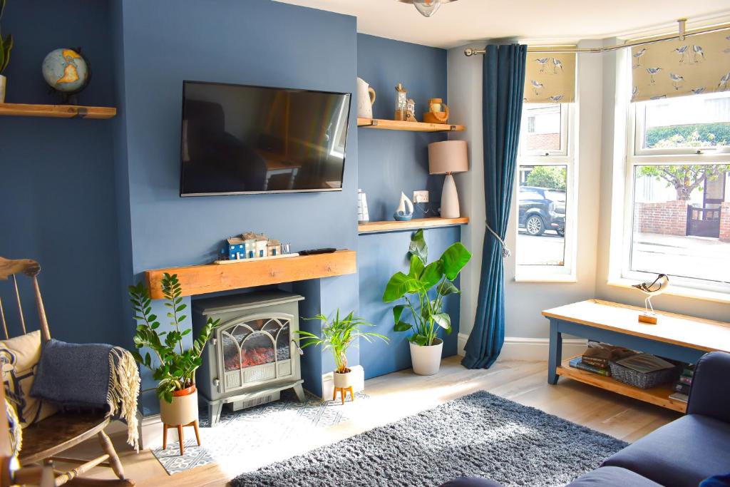 a living room with blue walls and a fireplace at Avocet - Suffolk Coastal Escapes in Pakefield