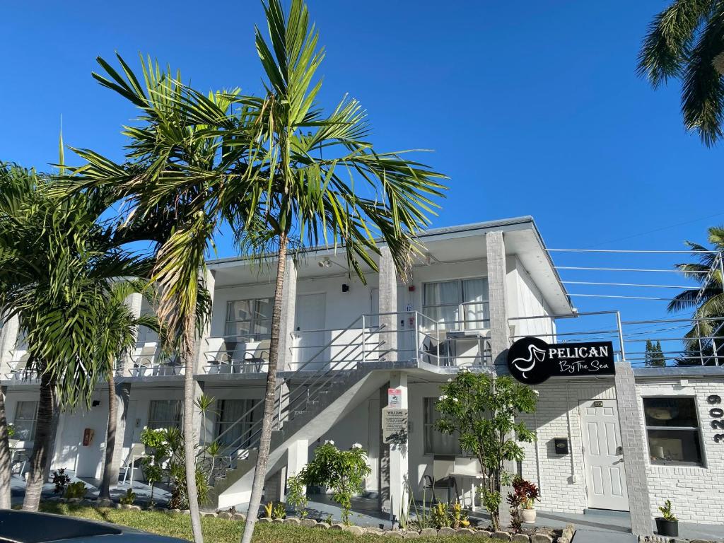 a palm tree in front of a white building at Pelican By The Sea in Pompano Beach