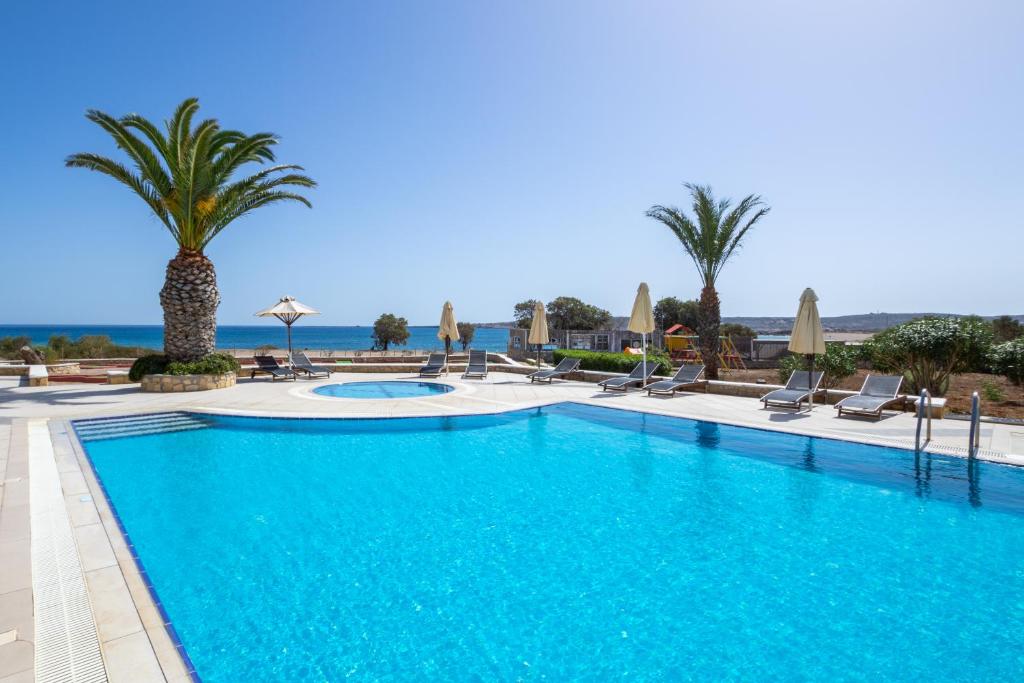 a large swimming pool with palm trees and chairs at Irini Hotel in Afiartis