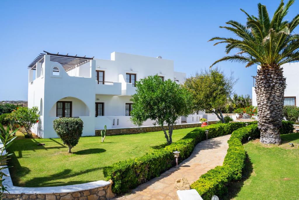 a white house with a palm tree and a garden at Irini Hotel in Afiartis