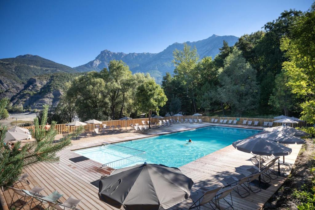 - une piscine avec des parasols et une piscine pour une personne dans l'établissement Huttopia Lac de Serre-Ponçon, à Le Lautaret