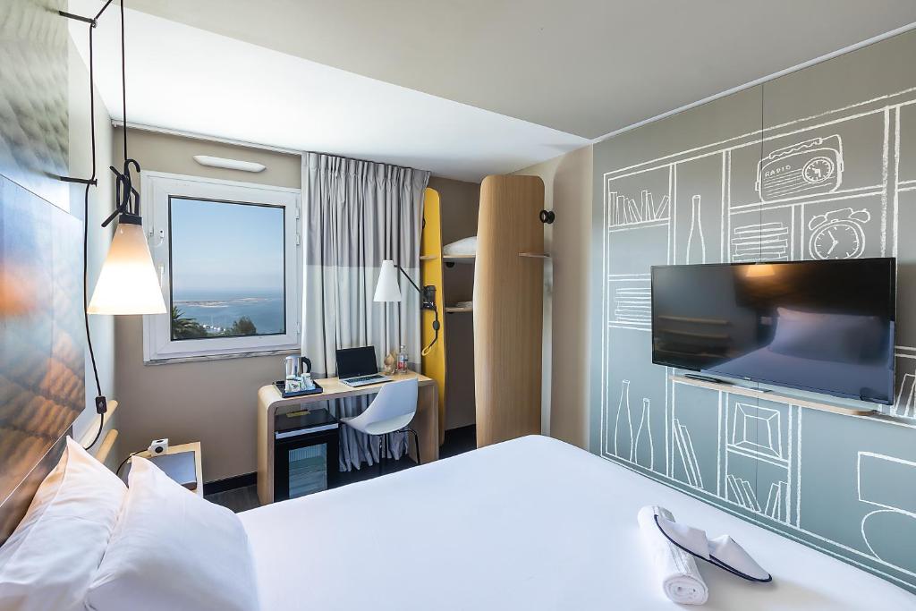 ヴィラ・ノヴァ・デ・ガイアにあるHotel ibis Porto Gaiaのベッドとデスクが備わるホテルルームです。