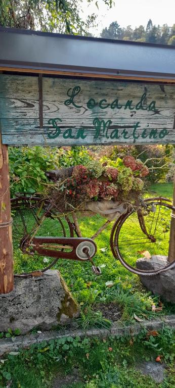a bike with flowers on it sitting under a sign at Locanda San Martino in Massac