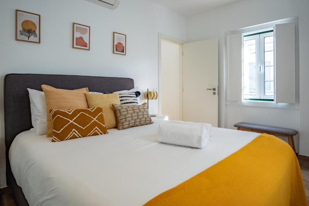 una camera da letto con un grande letto bianco con cuscini di Feel Nazaré - Abegoarias 62 a Nazaré