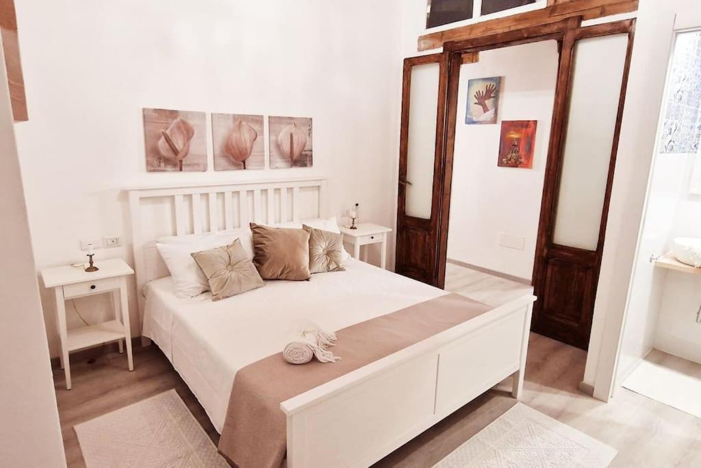 una camera da letto con un grande letto bianco e due tavoli di Holiday Home Virgilio House a Cagliari