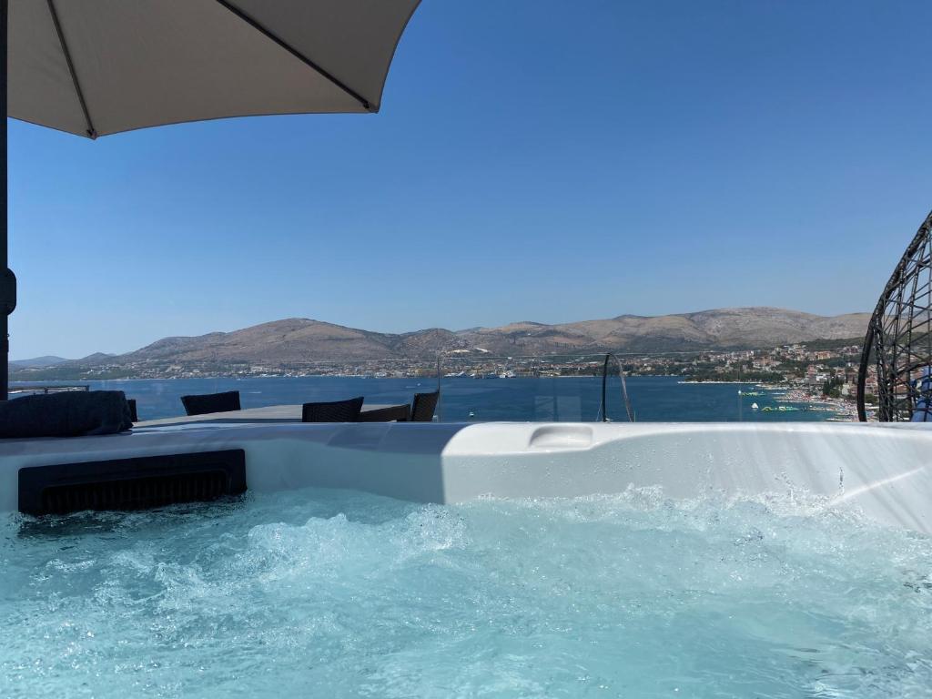 a swimming pool with an umbrella next to the water at Penthouse Maus in Trogir