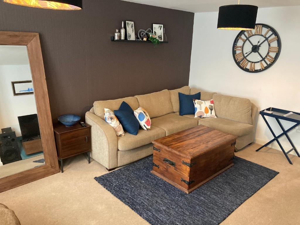 a living room with a couch and a clock on the wall at Cheerful Home FOR FOOTBALL, DOCKS AND CITY CENTRE in Liverpool
