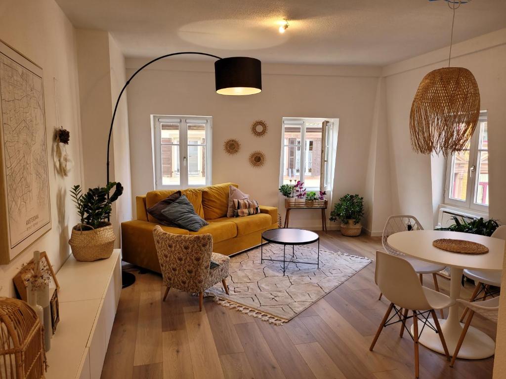 ein Wohnzimmer mit einem gelben Sofa und einem Tisch in der Unterkunft Chaleureux 2 pièces au centre de Haguenau in Haguenau