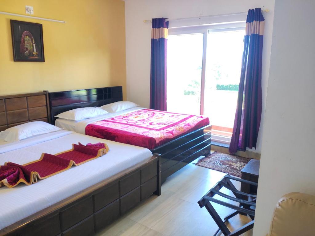 two beds in a small room with a window at Forest Gate in Ooty