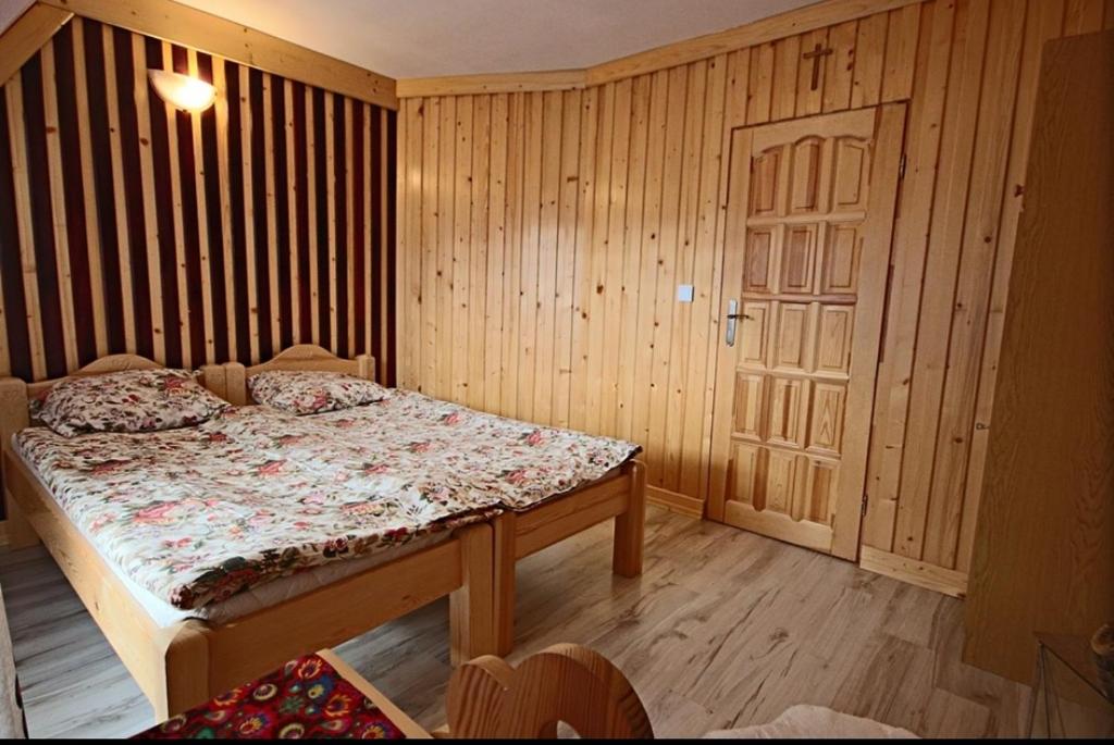a bedroom with a bed and a wooden wall at Dom Wczasowy Salamon in Poronin