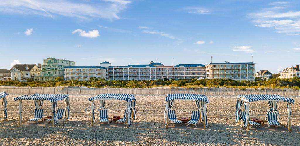 um grupo de cadeiras e mesas na praia em La Mer Beachfront Resort em Cape May