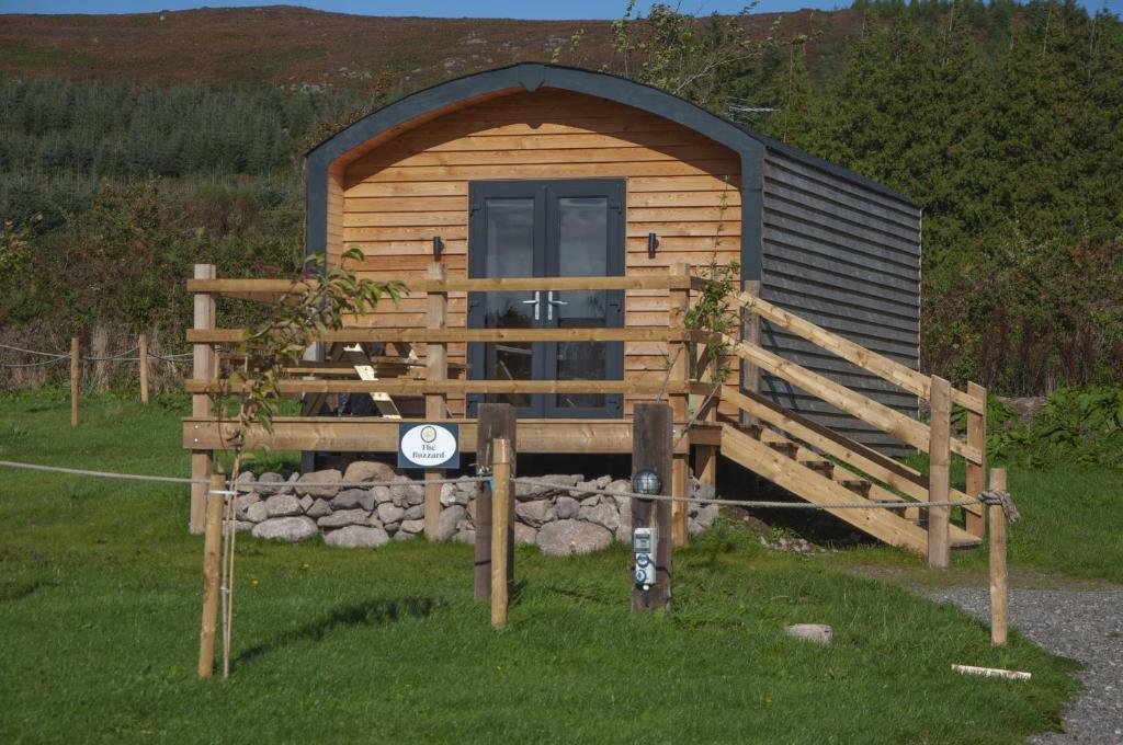 Cabaña de madera con puerta y valla en The Buzzard - 6 Person Family Glamping Cabin, en Dungarvan