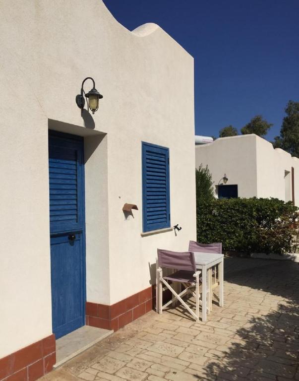 a white building with a blue door and a table at Petruso Resort in Balestrate